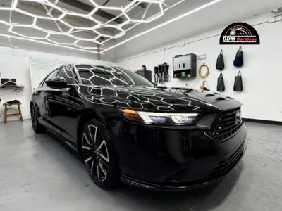 Three-quarter view of a glossy black Honda Accord featuring paint protection film