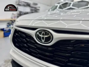 Close-up of a white Toyota front grille and emblem, highlighting the seamless edges of a professional vinyl wrap application.