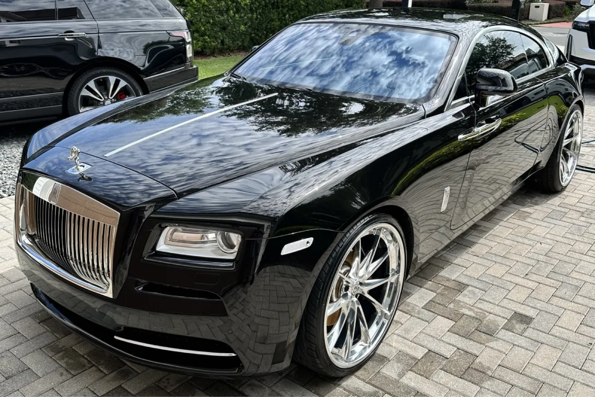 Front angle of black Rolls Royce with chrome wheels and reflective paint