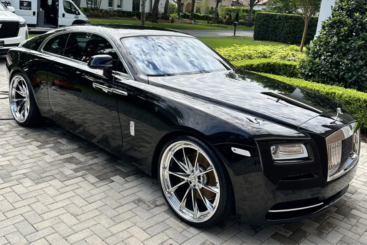 Black Rolls Royce coupe with glossy finish parked on driveway