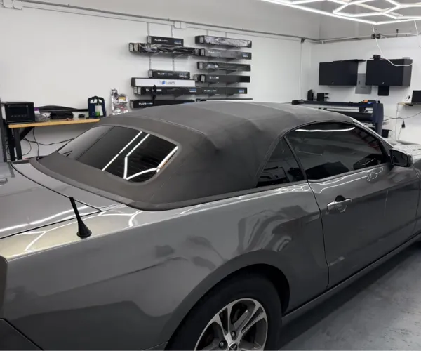 A professional applying a protective film layer to the glossy white exterior of a vehicle.