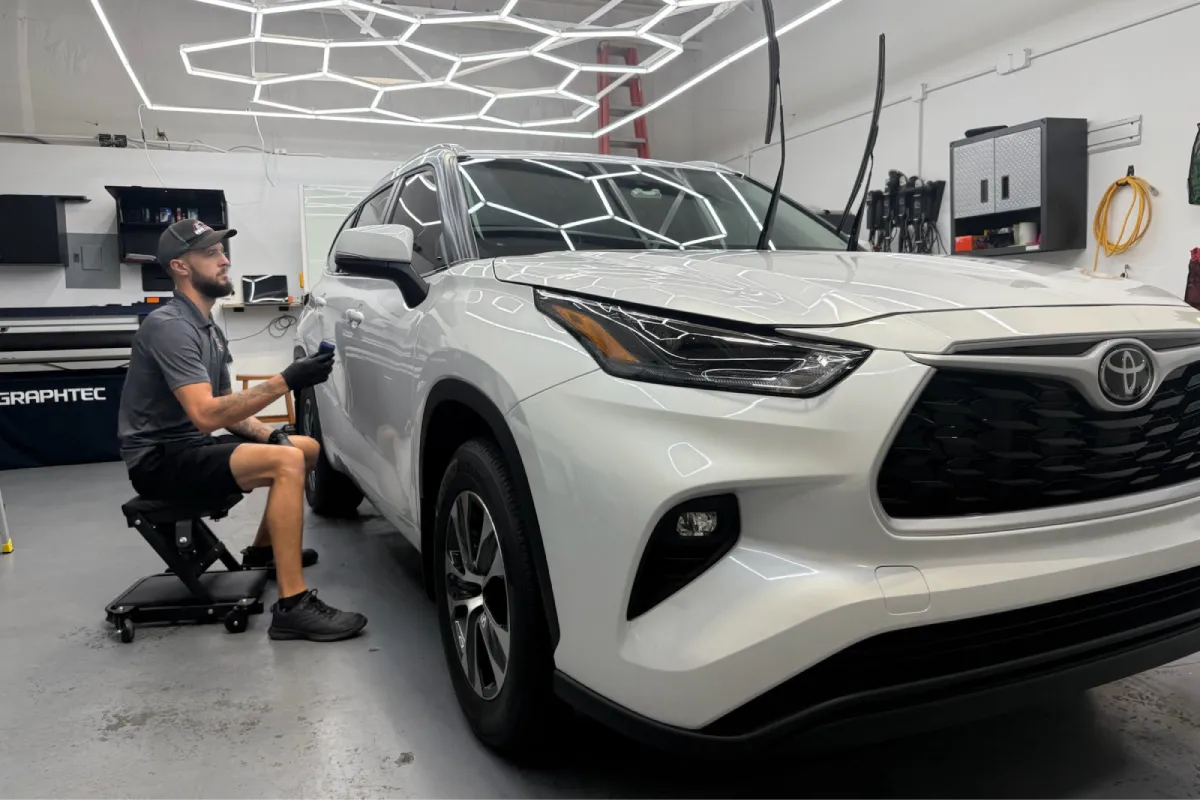 Technician applying paint correction on the rear of a white vehicle.