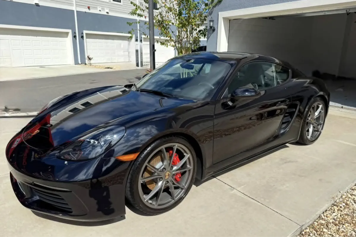 Ceramic coated black Porsche parked outside a garage.