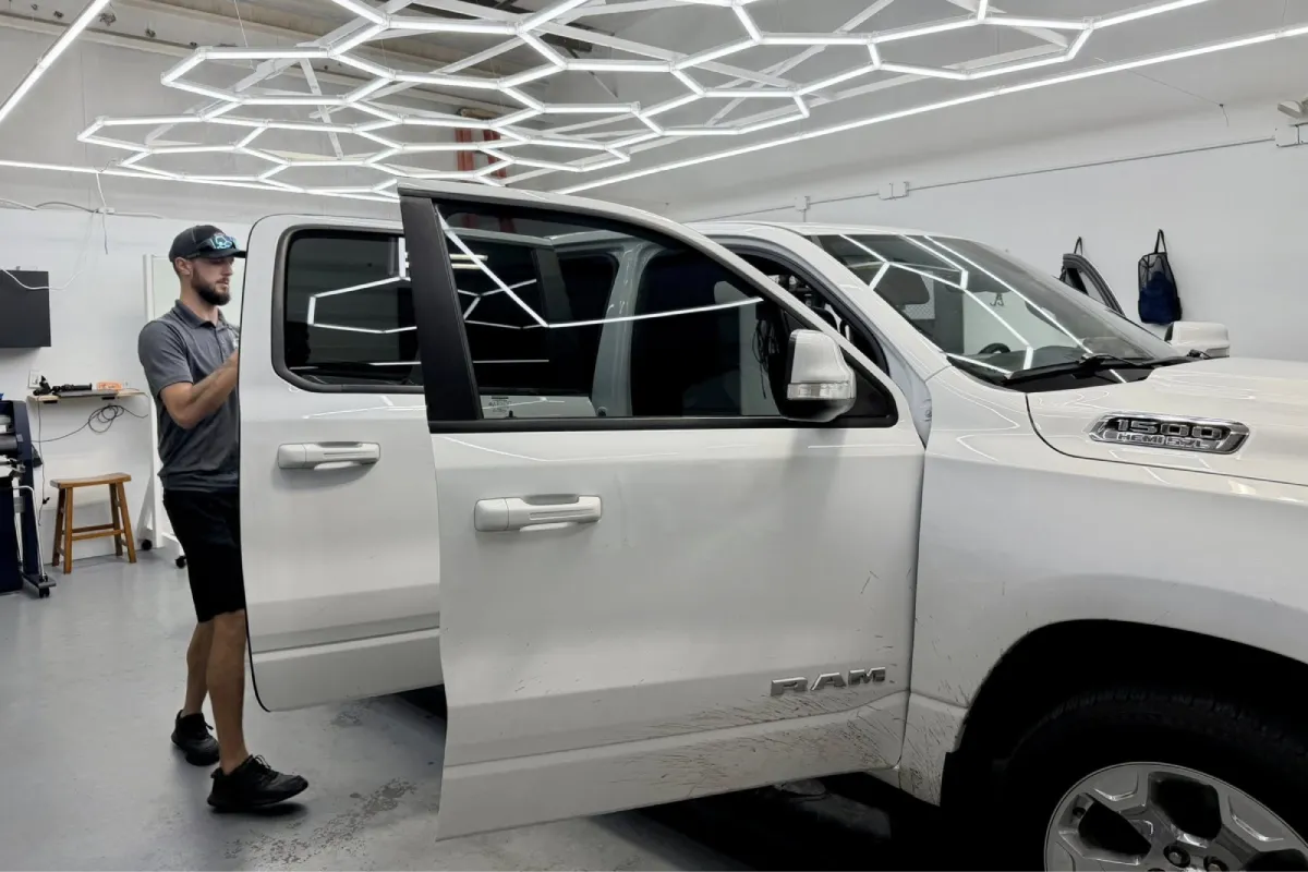 A technician working on the driver's side window tinting of the same truck.